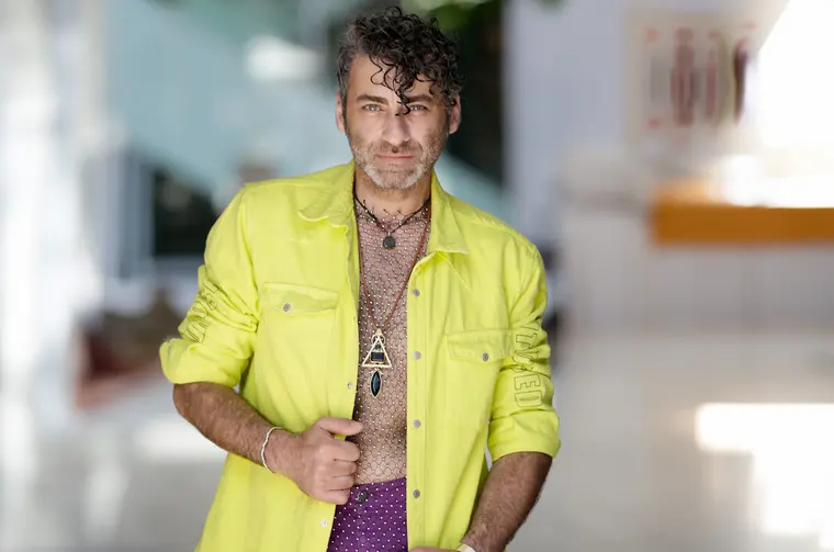 Wladimir Arutti in einem neongelben Hemd über einem gemusterten Oberteil, mit Kette und Ringen.