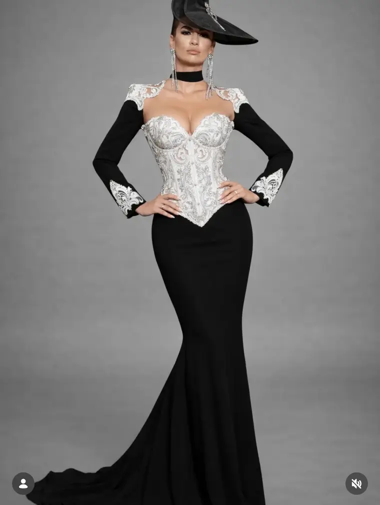 Bodenlange schwarze Robe mit weiss gefasstem Korsagenoberteil und langen Handschuhen vor grauem Grund.