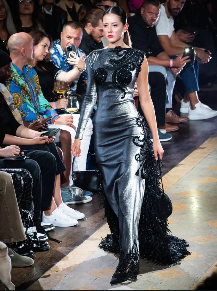 Kate Winterberg auf dem Laufsteg in einer langen schwarzen Robe.